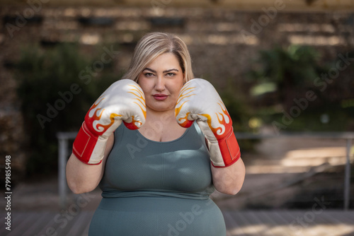 Curvy woman wearing boxing gloves in park photo