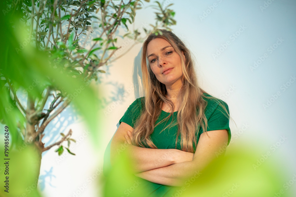 Confident businesswoman standing with arms crossed by plants Confident businesswoman standing with arms crossed by plants