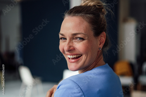 Happy businesswoman looking back over shoulder in office photo