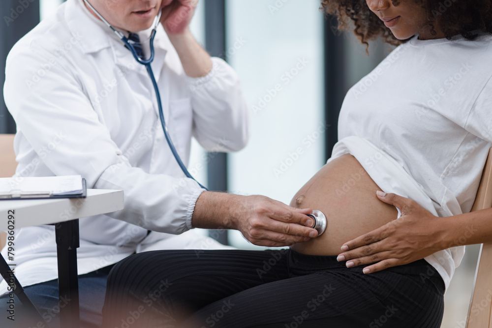 Fototapeta premium Male doctor examining a pregnant African American woman at the hospital.