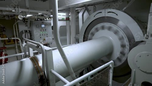 Motor room of ship. Main shaft with a large disc rotates. Shaft from engine to propeller