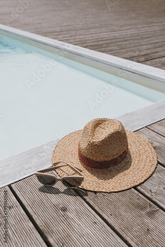 Relaxing, sunbathing at resort swimming pool. Straw hat, sunglasses at poolside. Summer vacation holidays