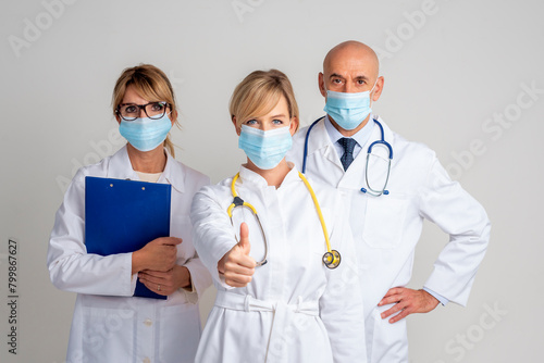 Group of healthcare worker wearinc surgical mask and standing together and isolated background