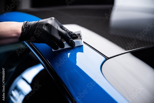Car cash or car detailing studio worker applying graphene or ceramic coating on blue sport car. photo