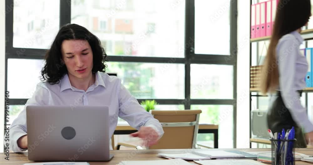 Annoyed male manager works on laptop and asks to leave approaching female colleague angrily. Busy boss chases away employee sitting at table in office