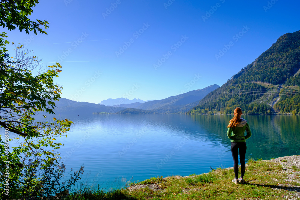 Hiker looking at lake Walchensee under blue sky in Upper Bavaria, Bavaria, Germany Hiker looking at lake Walchensee under blue sky in Upper Bavaria, Bavaria, Germany