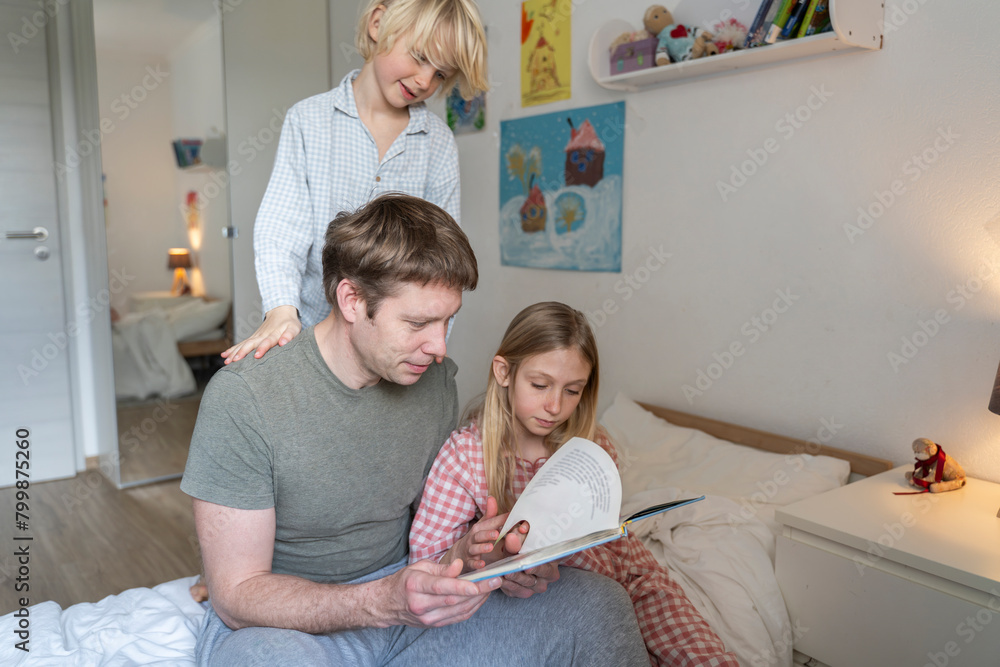 Father reading book to children on bed at home Father reading book to children on bed at home