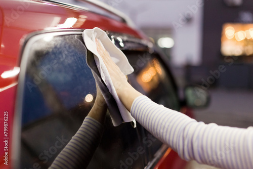 Woman wiping car with napkin after wash at garage photo