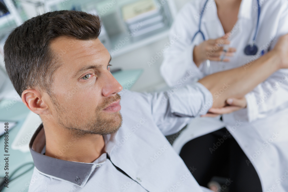man looking away as doctor prepares to inject him