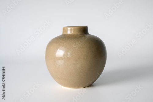 A small vase with a brown color sits on a white background. The vase is empty and has a simple design. Concept of calmness and simplicity