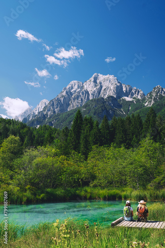 Couple tourists enjoying green nature outdoors. Amazing view on Zelenci (into English means - green) nature reserve and Alps mountains in Slovenia, Europe. People in nature background. Travel concept.