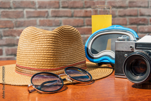 Tourist still life. A hat, sunglasses, and a camera are on a table