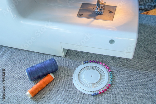 A sewing machine with a spool of thread and a pin needle on a table