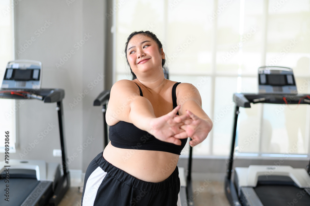 Happy Overweight Asian woman stretching before some main exercises in gym. Weight loss workout, healthy lifestyle concept. Happy Overweight Asian woman stretching before some main exercises in gym. Weight loss workout, healthy lifestyle concept.