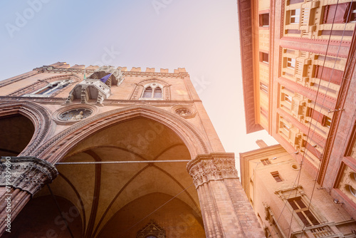 Gazing upward, this photo captures the intricate gothic arches of Palazzo della Mercanzia in Bologna, standing in harmony beside the city iconic twin towers photo