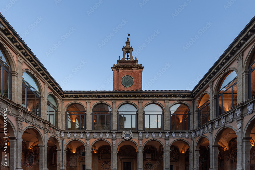 Golden hour light gently kisses the terracotta facade of the University of Bologna, framing the historical main entrance and its clock tower, a portal to centuries of academic excellence