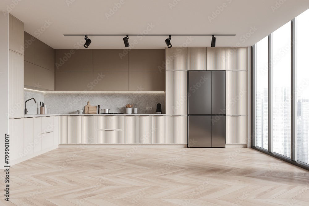 Fototapeta premium A sleek modern kitchen interior with a herringbone floor, beige cabinetry, and daylight coming from large windows. 3D Rendering