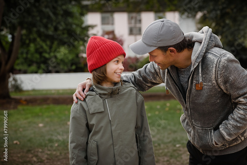 Portrait of happy teenage boy talking to his father and having fun, Joyful bonding: Teenage boy shares laughter and conversation, creating happy moments with his father.