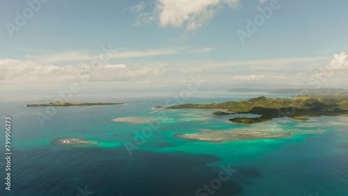 Coral atoll with blue water and a tropical island in the ocean on a sunny day. Bucas grande, Philippines. Summer and travel vacation concept. photo