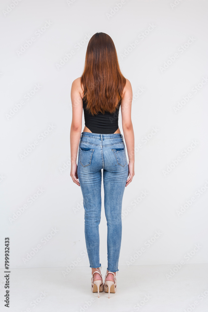 Fototapeta premium Young Asian woman in black bodysuit and jeans from behind, isolated on white