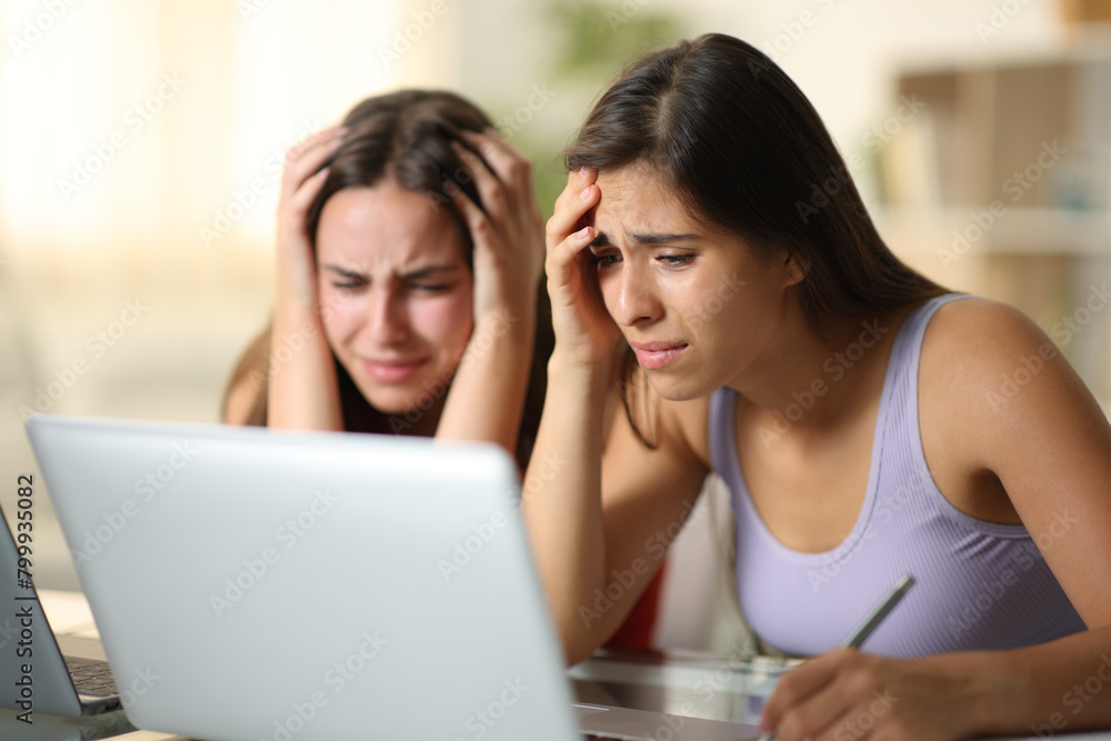 Worried women complaining checking laptop content Worried women complaining checking laptop content