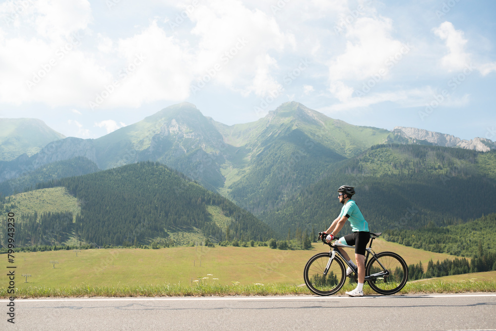 Active man on bike in the middle of beautiful nature, admire mountains, standing by bicycle. Concept of healthy lifestyle.