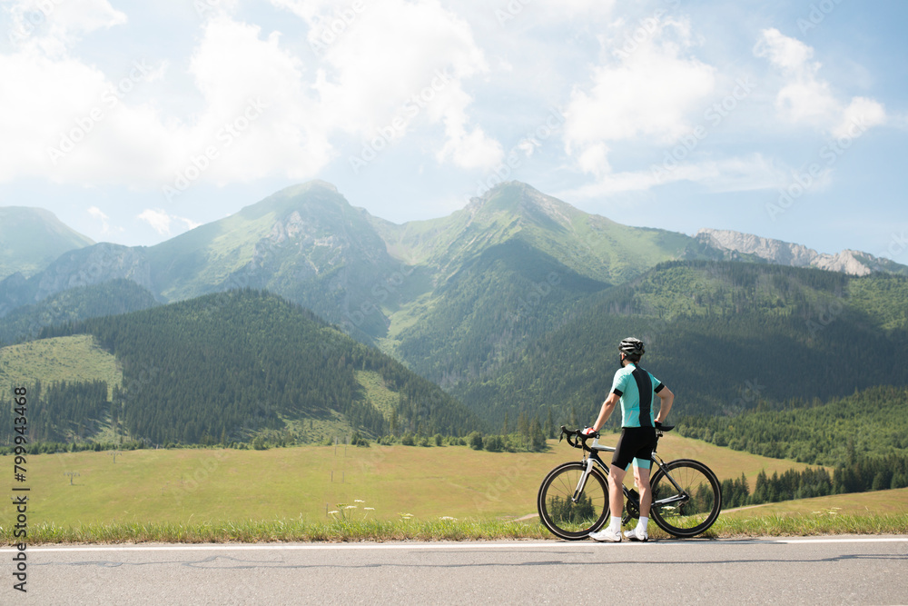 Active man on bike in the middle of beautiful nature, admire mountains, standing by bicycle. Concept of healthy lifestyle.