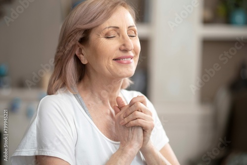 Beautiful woman 50 years old enjoys yoga she is meditating by cupping her palms front her with her eyes closed she dreams personal one close up shot