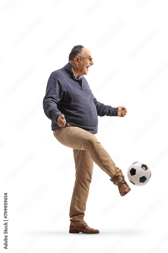 Full length profile shot of a casual mature man kicking a football