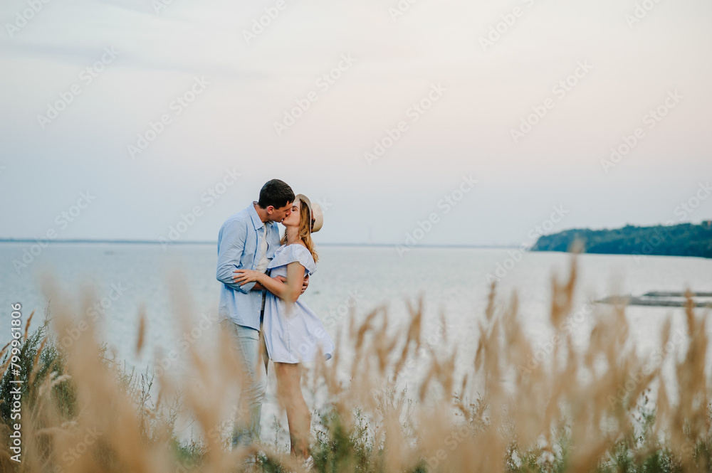 Man and woman kiss and embrace on sand sea spending time together. Couple in love standing and kissing on edge of cliff on seashore. Female and male on beach ocean and enjoying sunny summer day.