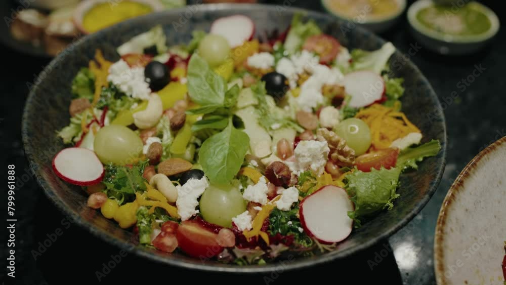 Closeup on bowl with fresh salad, mix of lettuce leaves, tomato, radish, nuts, grape and cheese. Vegetarian salad in cafe. Delicious and healthy food Closeup on bowl with fresh salad, mix of lettuce leaves, tomato, radish, nuts, grape and cheese. Vegetarian salad in cafe. Delicious and healthy food