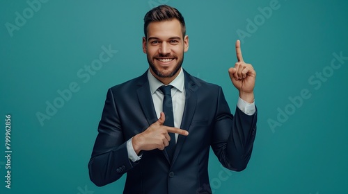 A man in a suit is smiling and pointing with two fingers.