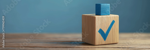 A close-up of a wooden cube with a blue checkmark against a calm blue background, signifying approval or correctness photo