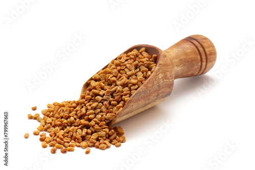 Front view of a wooden scoop filled with dry Organic Fenugreek seeds (Trigonella foenum-graecum). Isolated on a white background.