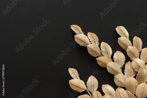 The branch with leaves is made of straw. Straw wall decoration. The products are made of straw. Straw weaving. Blank space for a text.