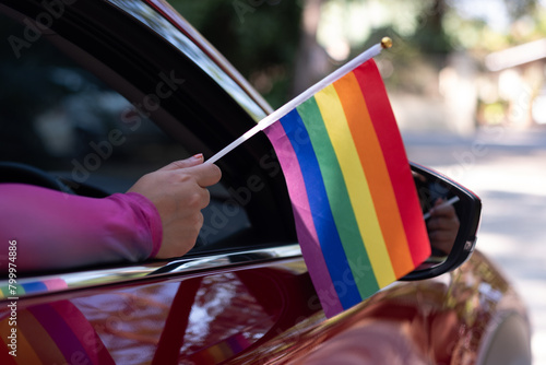 Hand holding a pride flag out the car window