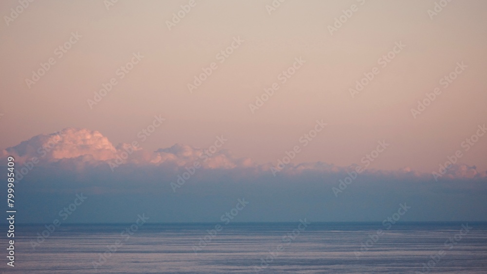 Fluffy clouds sunset sky above calm sea with space for text. Miminal coastal banner. Fluffy clouds sunset sky above calm sea with space for text. Miminal coastal banner.