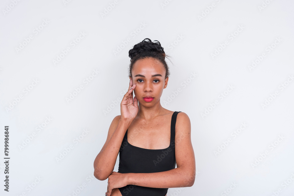 Confident mixed-race woman in black bodysuit standing against a white background Confident mixed-race woman in black bodysuit standing against a white background