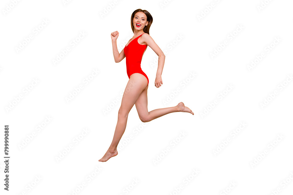 Run to meet the summer. Full-legs portrait of fit sporty girl inred swimsuit jumping over in the air looking at camera isolated on yellow background