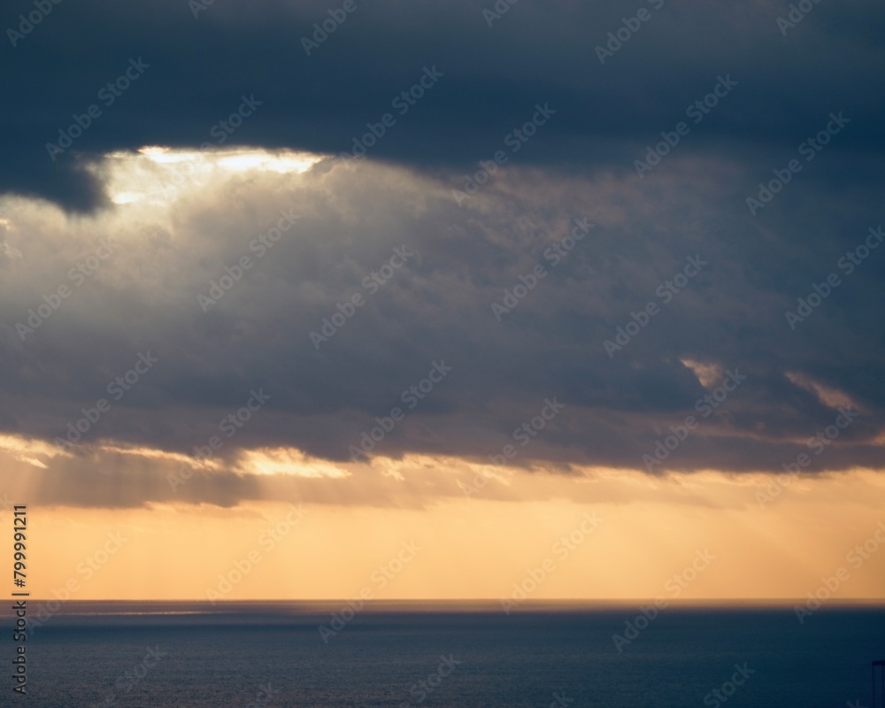 Rays of light emerge from behind storm clouds at sunset over the Mediterranean Sea.
