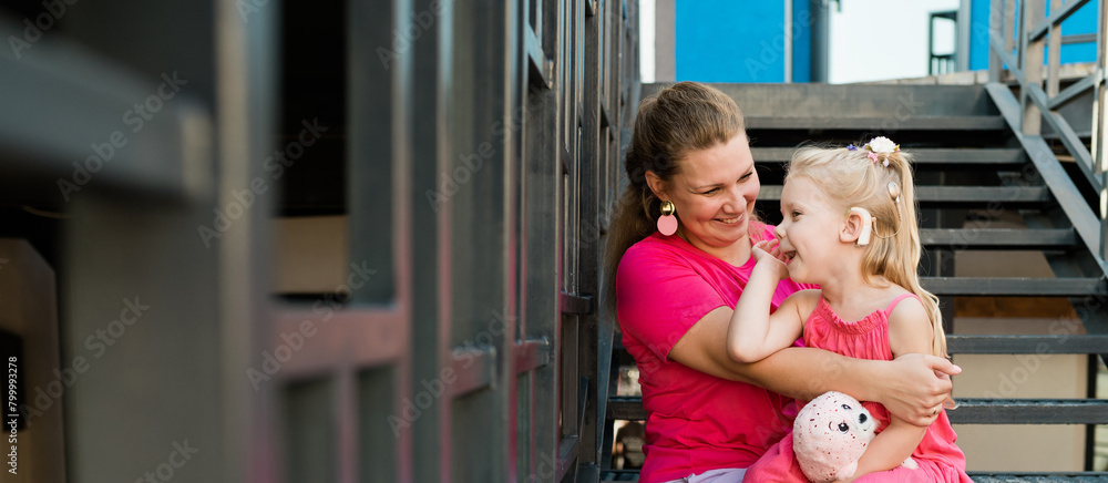Εκτύπωση καμβά Blonde little girl with cochlear implant playing with her mother outdoor