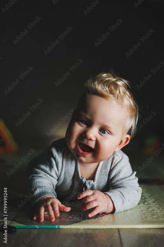 An 8-month-old child is lying on the floor and gnawing on a teether. Baby plays with toys An 8-month-old child is lying on the floor and gnawing on a teether. Baby plays with toys