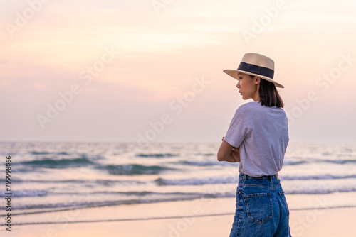 Sadly and depressed asian woman standing with arms crossed on the beach near the sea alone. Bad feelings, through. Loneliness person. Depression Concept. Girl sit alone and think about her.