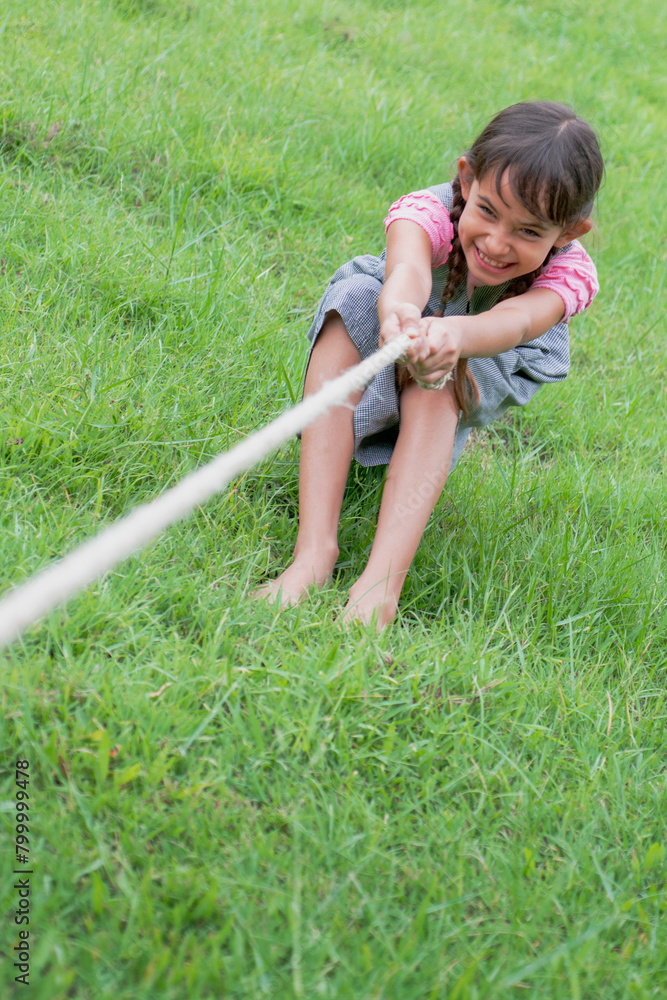 Pretty little girl having fun, playing tug war game pull string at the ...