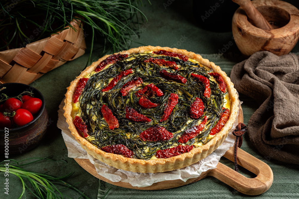 Φωτογραφία Italian rustic savory pie made with pie crust, salsola soda or agretti, ricotta cheese, eggs and dried tomatoes on a green wooden table