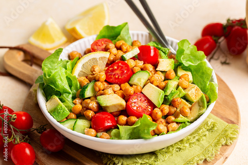 Plate with Mediterranean Chickpea Salad. Chickpea and paprika Baked Beans, lettuce, tomatoes, avocado, cucumber, lemon and olive oil dressing. Healthy high protein vegan meal.