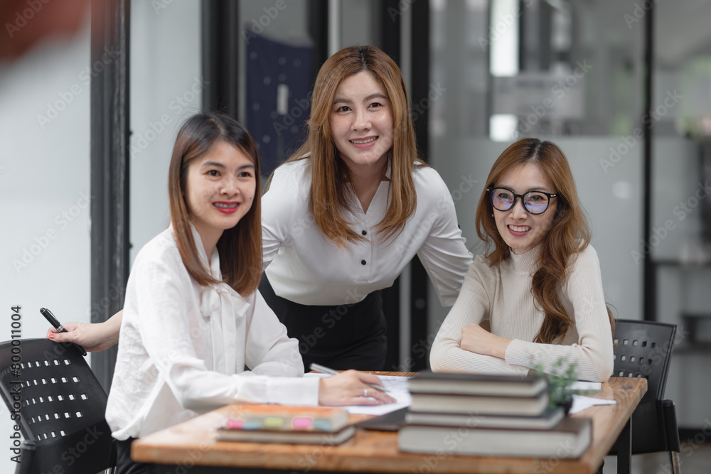 Group of young asian businesswoman working and brainstorming in workshop and analyzing marketing reports startup project infographics in the office. Group of young asian businesswoman working and brainstorming in workshop and analyzing marketing reports startup project infographics in the office.