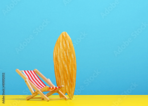 Beach chair and surf board on blue and yellow background.