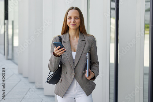 Free Download An attractive business woman with a mobile phone against the background of modern neighbourhoods. Freelance, money, work, career - GFXLoad