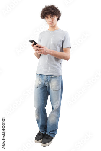 Young man, smiling and handsome, using his smartphone with earphones to listen to music or voice message. He looking into the camera with his blue eyes, isolated on white background in full-body shot